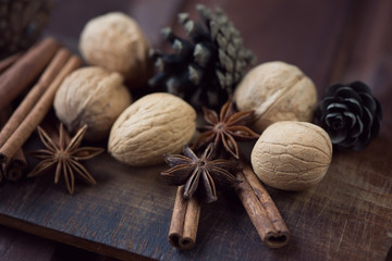 Walnuts, cinnamon, anise and fir-cones, rustic wooden surface