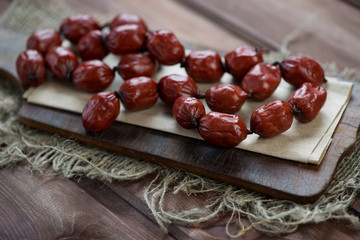 Smoked mini sausages on a wooden chopping board