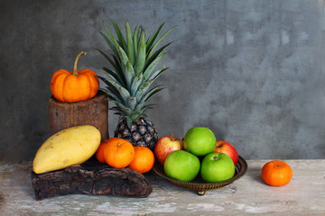 Still life apple, pineapple,pumpkin  tangerine and mango on wood