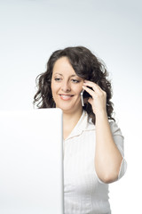 Young woman in front of laptop talking on the phone