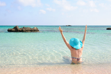 Fototapeta na wymiar Beautiful young woman with sunhat, relaxing on a sunny beach