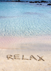 Relax word written in the sand, on a beautiful beach