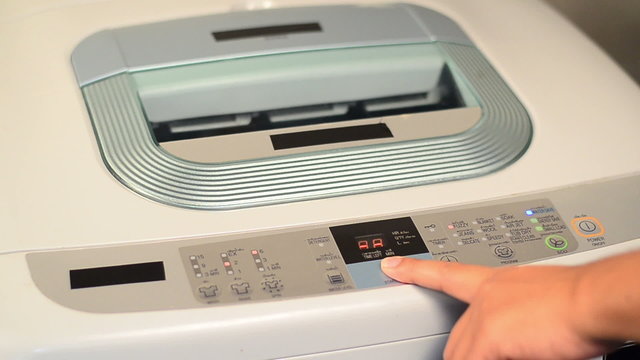 Male hand press power button to start washing machine