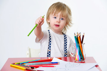 Cute kid holding one of his colorful crayons during art class