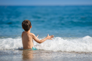 Fototapeta premium Portrait of little boy splashing in ocean waves