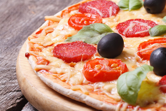 pizza with salami, tomato, olives and basil close-up