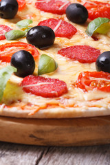 pizza with salami, tomato, olives and basil. vertical.