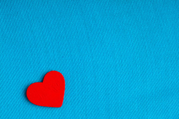 Fototapeta premium Red wooden decorative heart on blue cloth background.