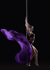 Young slim pole dancer posing with violet cloth