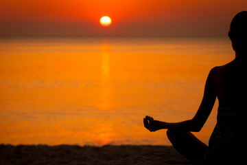 Woman doing Yoga at sunset