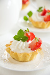 Tartlets with whipped cream and strawberries.