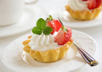 Tartlets with whipped cream and strawberries.