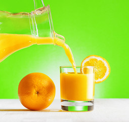 Orange juice pouring from jug into a glass