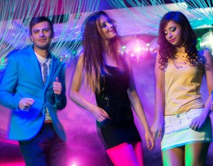 Group of happy young people dancing at night club