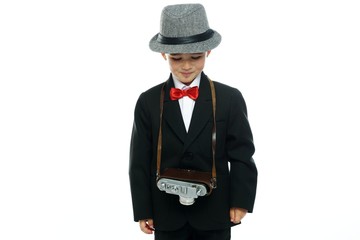 Little boy in hat and black suit with vintage camera 