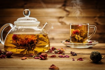 Teapot and glass cup with blooming tea flower inside 
