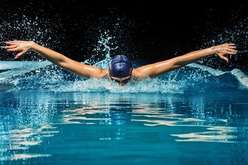 Young woman in blue cap and swimming suit in pool - obrazy, fototapety, plakaty