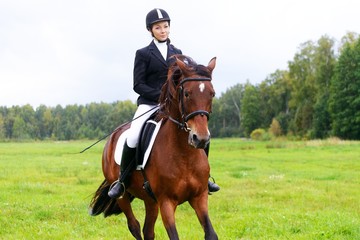 Cheerful young woman ridding horse in a field