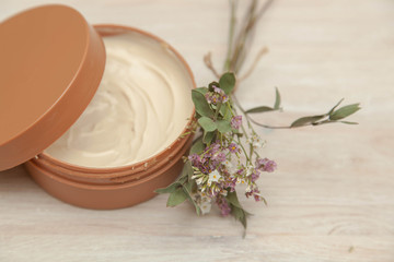 body cream and wildflowers on wooden table
