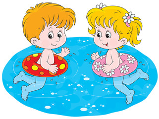 girl and boy with swimming rings in blue water