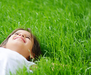 Happy little boy enjoying on grass field and dreaming