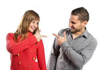 Couple pointing each other over white background