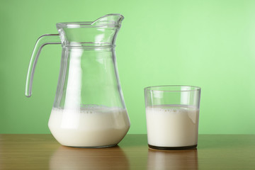 Vaso y jarra de leche sobre fondo verde