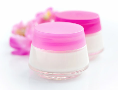 Cosmetic creams  and pink flowers isolated on white background