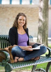 Portrait Of Happy Student Studying On Bench