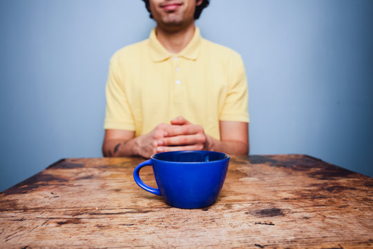Young man sitting at table with cup of coffee