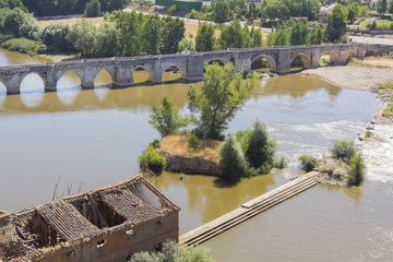 Obraz premium Ruins of warehouse next to a river and a bridge