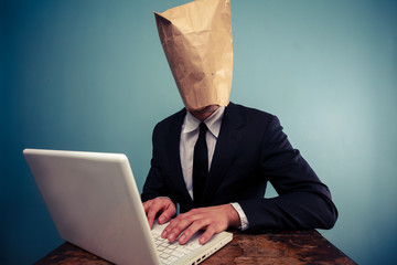 Businessman with bag over head working on computer