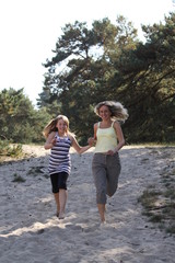 Tochter und Mutter rennen durch die Dünen