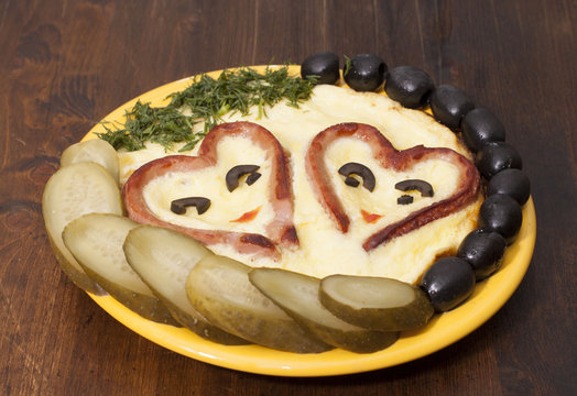 Heart-shaped sausages with fried eggs, pickles and olives.