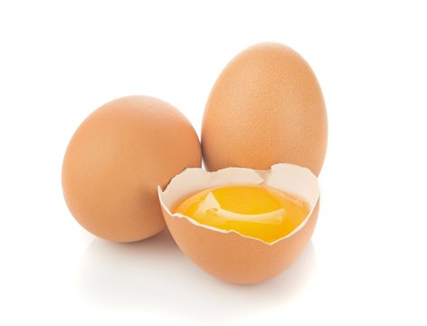 A separated egg yolk and eggs on a white background
