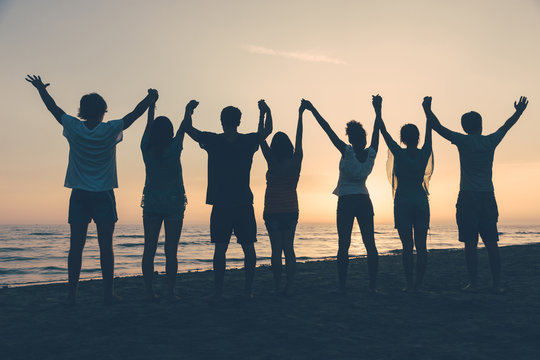 Group of People with Raised Arms looking at Sunset