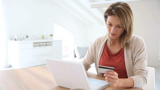 Cheerful middle-aged woman buying on internet