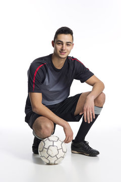 junger Fussballer in der Hocke mit Fussball