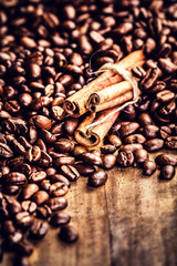 Roasted Coffee beans and cinnamon sticks on grunge wooden backgr