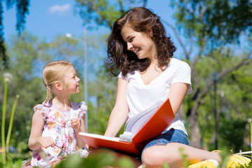 girl and a young woman reading a book together