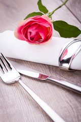 romantisch gedeckter tisch mit silberbesteck und einer rose