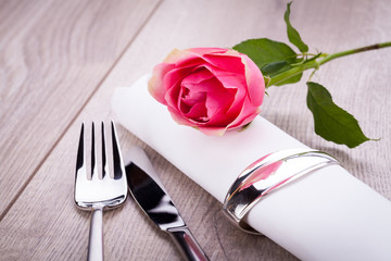 romantisch gedeckter tisch mit silberbesteck und einer rose
