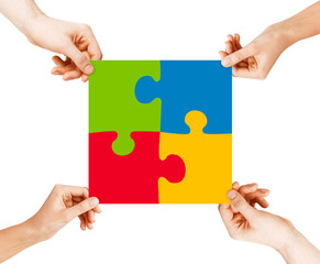 four hands connecting puzzle pieces
