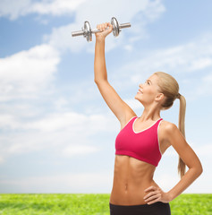 smiling woman lifting steel dumbbell