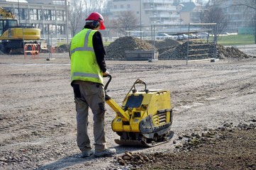 ouvrier utilisant une plaque vibrante