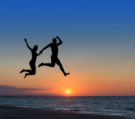 loving couple jumping highly in the sky at beach resort