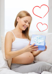 smiling pregnant woman opening gift box