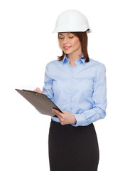 smiling businesswoman in helmet with clipboard