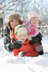 Fototapeta na wymiar Mother with two children lying in snow