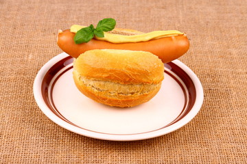 German sausage with bun, mustard and basil